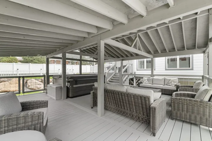 Custom-built covered gazebo deck with quality 6x6 construction, exposed beam ceiling, composite decking, and glass railings. Spacious design offers the perfect setting for outdoor gatherings and hot tub enjoyment
