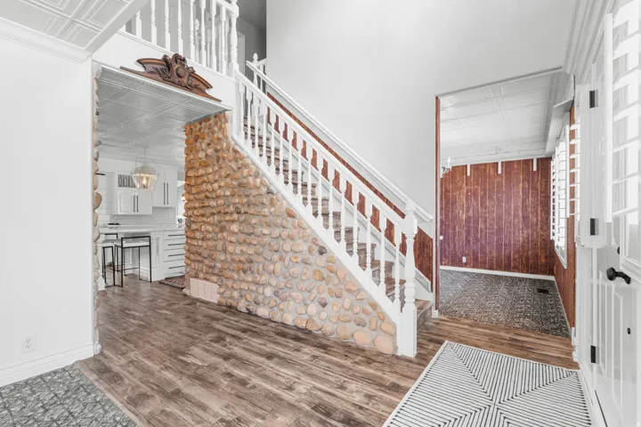 Welcoming foyer highlighted by a custom-built rock wall surrounding the staircase, adding warmth, texture, and architectural character