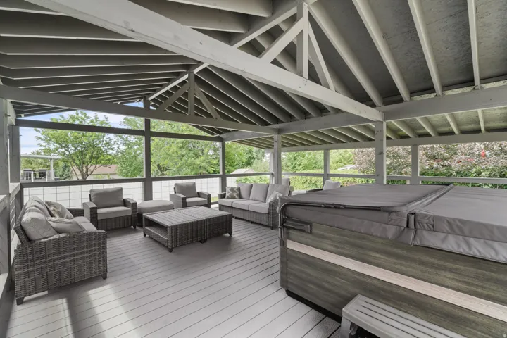 Custom-built covered gazebo deck with quality 6x6 construction, exposed beam ceiling, composite decking, and glass railings. Spacious design offers the perfect setting for outdoor gatherings and hot tub enjoyment