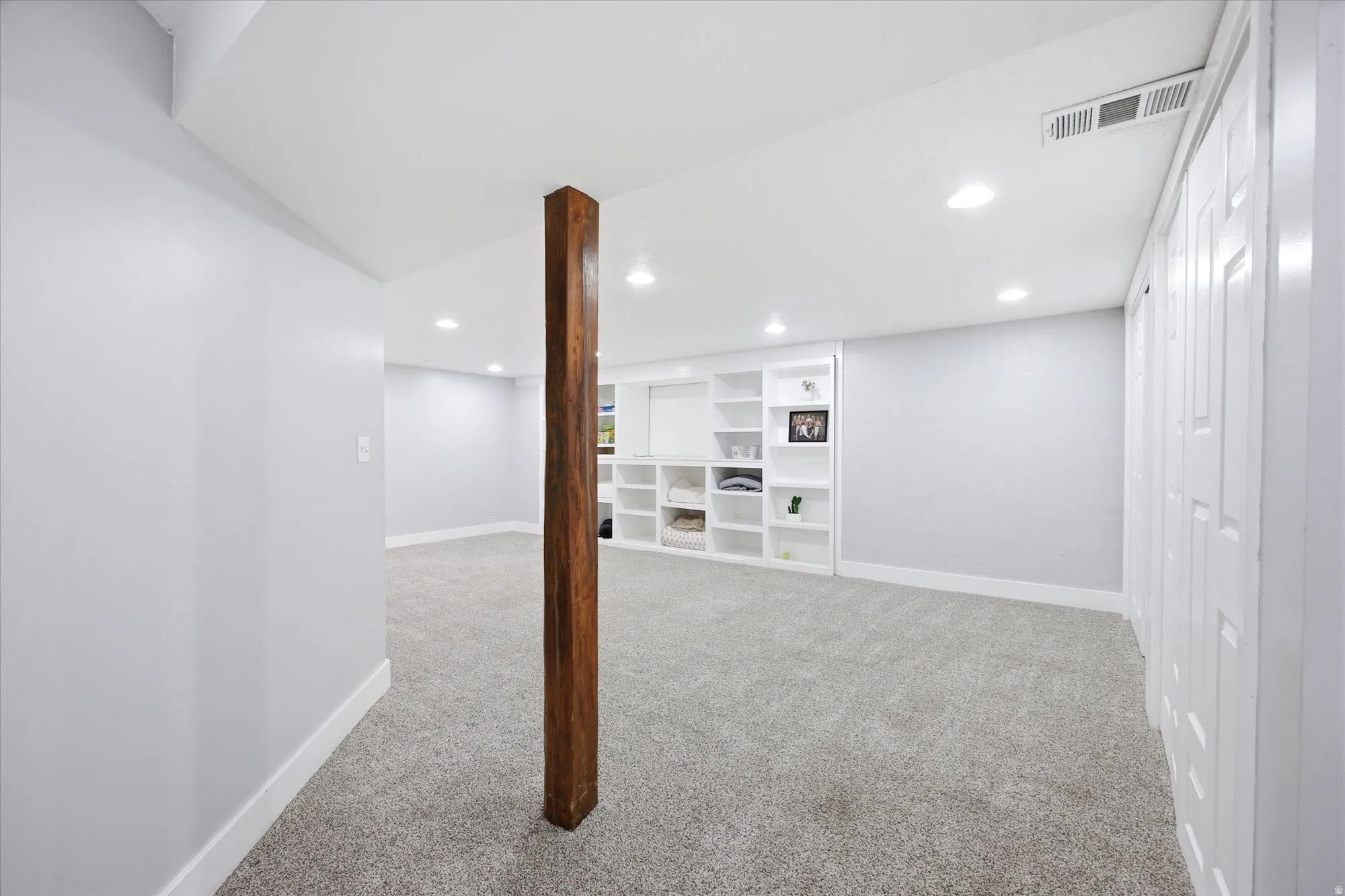Spacious room featuring light gray walls, recessed lighting, built-in shelving, gray carpeting, and white trim