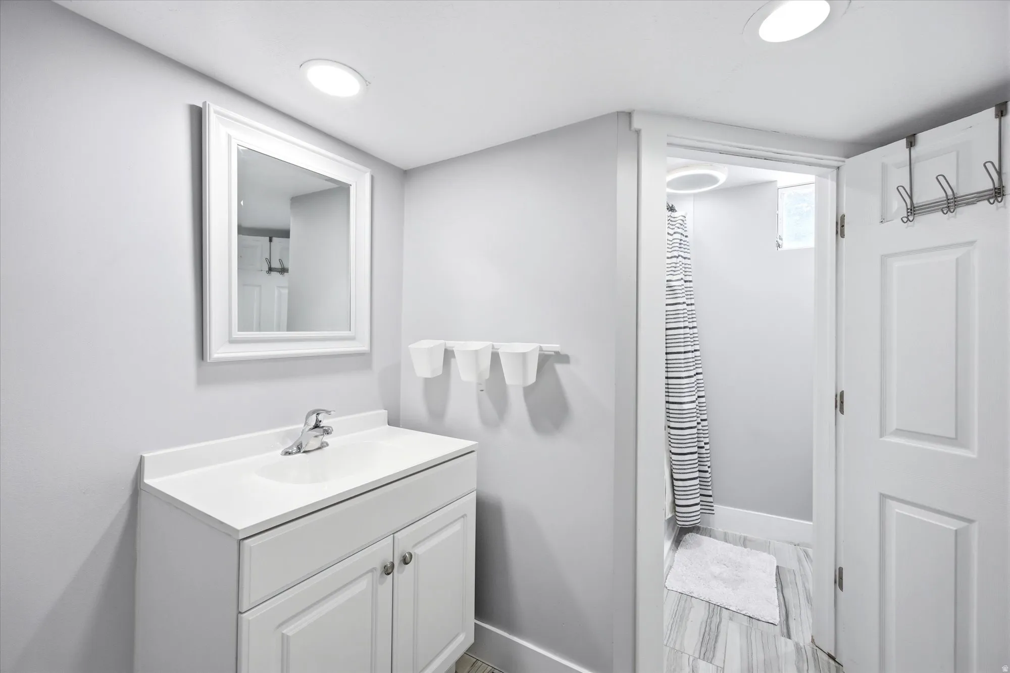Bathroom vanity featuring a white cabinet, integrated sink, chrome faucet, and framed mirror