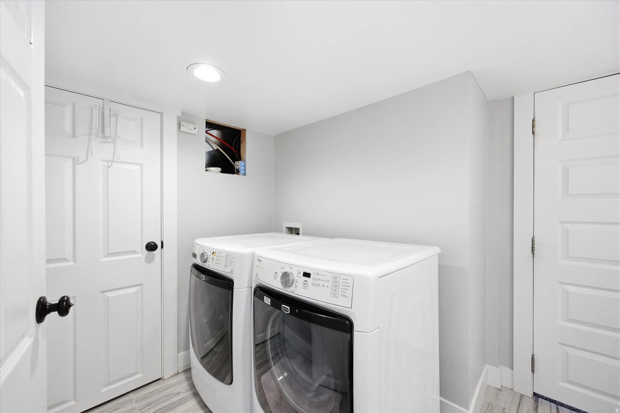 Dedicated laundry area featuring a front-loading washer and dryer set, white paneled doors, light gray wall paint, and recessed ceiling lighting