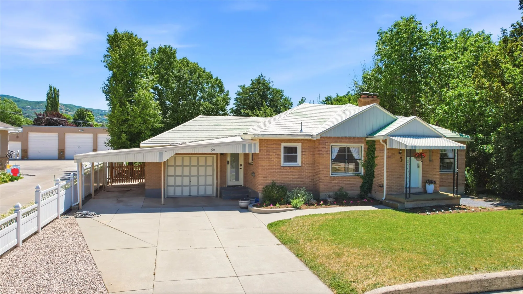Brick exterior residence featuring an attached carport, a single-car garage, and a covered front porch