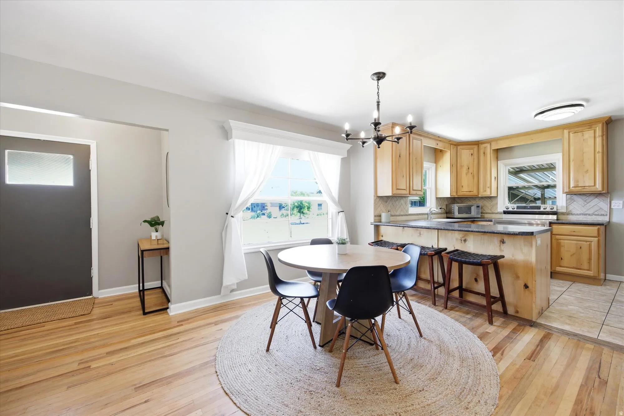 Open-concept kitchen and dining area featuring light wood cabinetry, a central island with bar seating, and a large window
