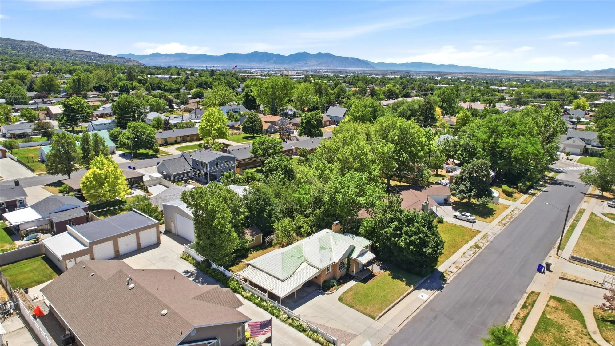 Aerial view of a residential area with mature trees and mountain ranges in the distance
