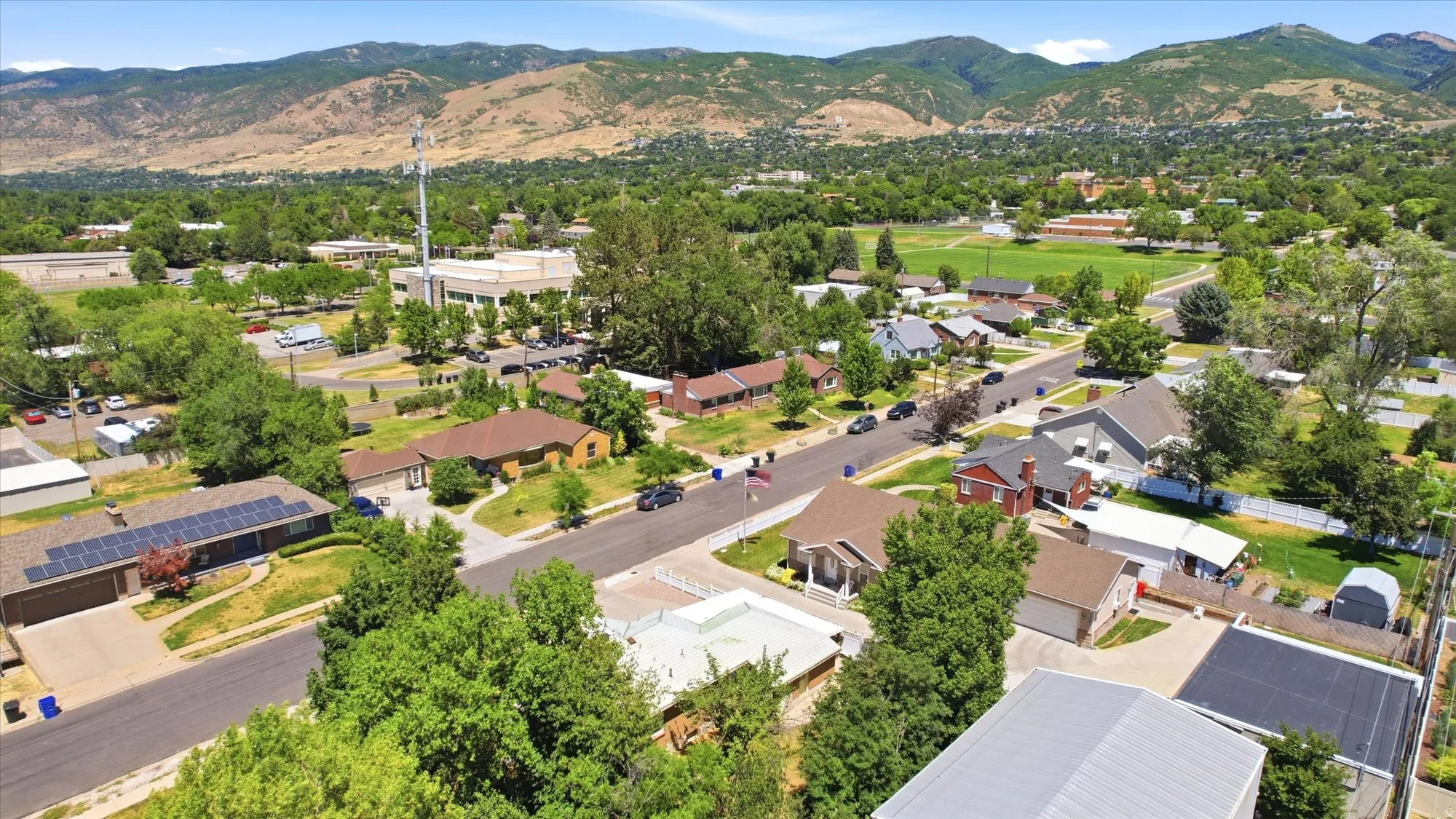 Aerial perspective showcasing a residential area with mature trees and mountain backdrops