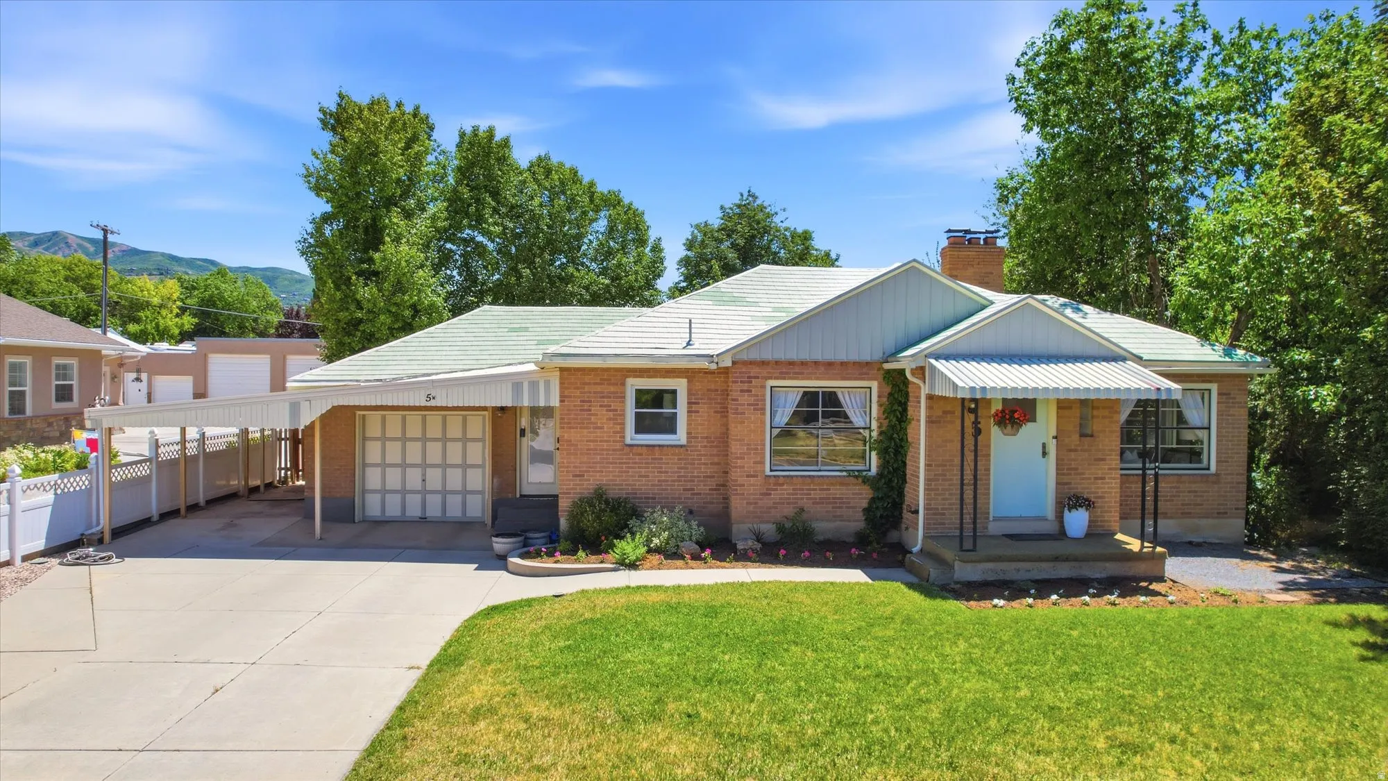 Brick single-story residence featuring a carport, front porch with awning, and a garage