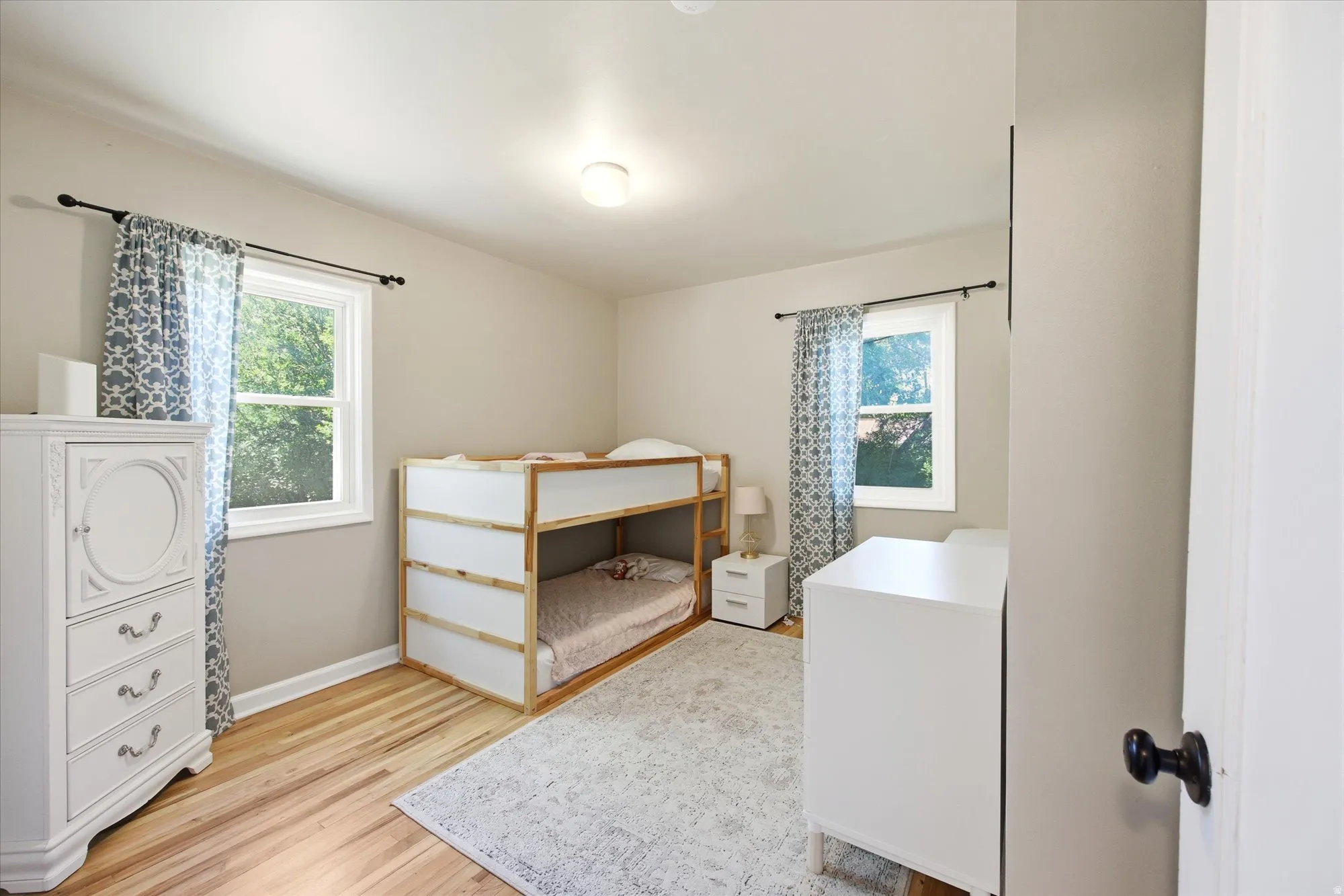 Warm interior room featuring wood-finish flooring, light neutral wall paint, and a flush mount ceiling light fixture