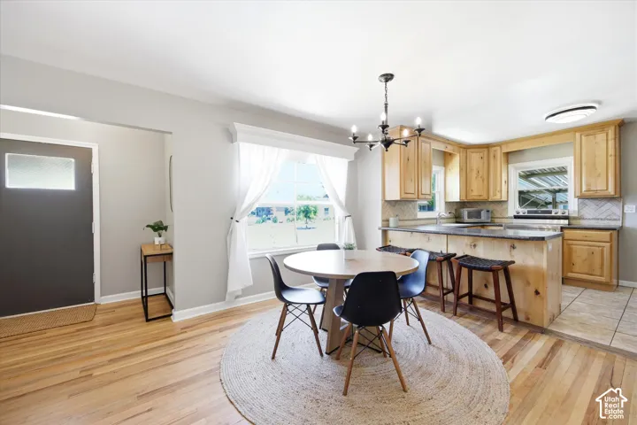 Open-concept kitchen and dining area featuring light wood cabinetry, a central island with bar seating, and a large window