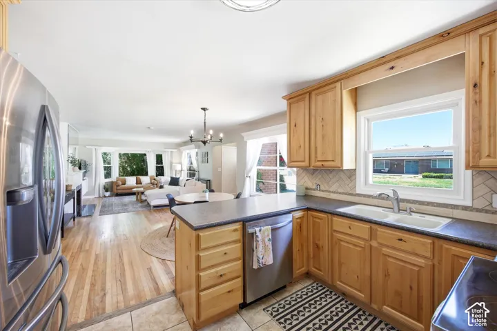 Kitchen featuring wood cabinetry, stainless steel appliances, dark countertops, and a tile backsplash, with a bright window overlooking the exterior