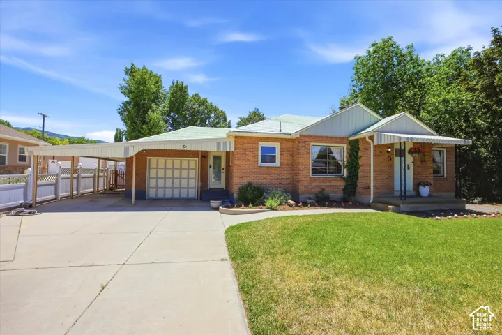 Brick exterior with an attached garage, covered carport, and a manicured front lawn