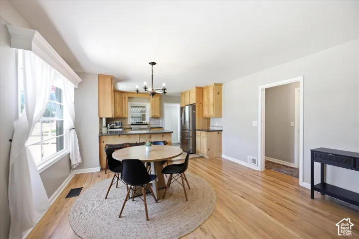 Open-concept living space featuring wood-finish flooring, a kitchen with natural wood cabinetry and stainless steel appliances, and a modern chandelier