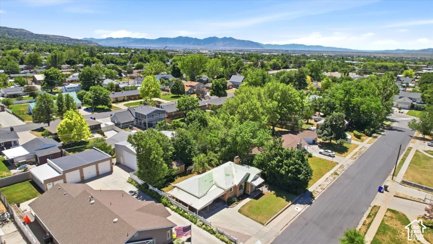 Aerial view of a residential area with mature trees and mountain ranges in the distance