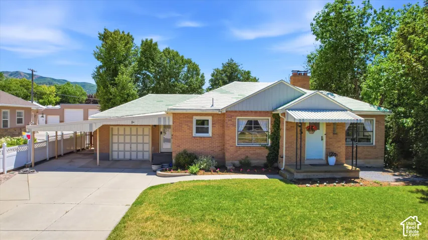 Brick single-story residence featuring a carport, front porch with awning, and a garage