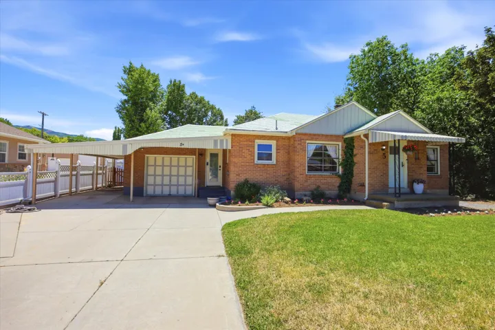 Brick exterior with an attached garage, covered carport, and a manicured front lawn