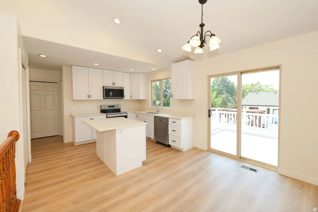 Bright kitchen and dining area featuring white cabinetry, stainless steel appliances, and a central island