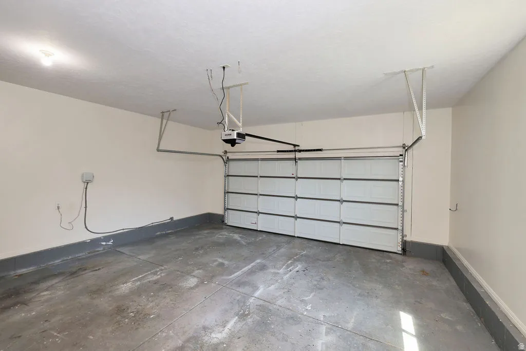 Single-car garage featuring a sectional garage door, concrete flooring, painted walls, and an overhead lighting fixture