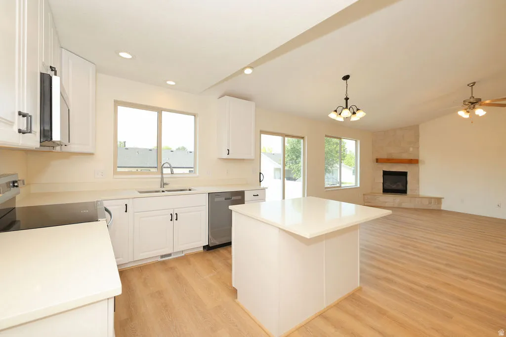 Open-concept living area featuring a kitchen with white cabinetry, stainless steel appliances, and a central island