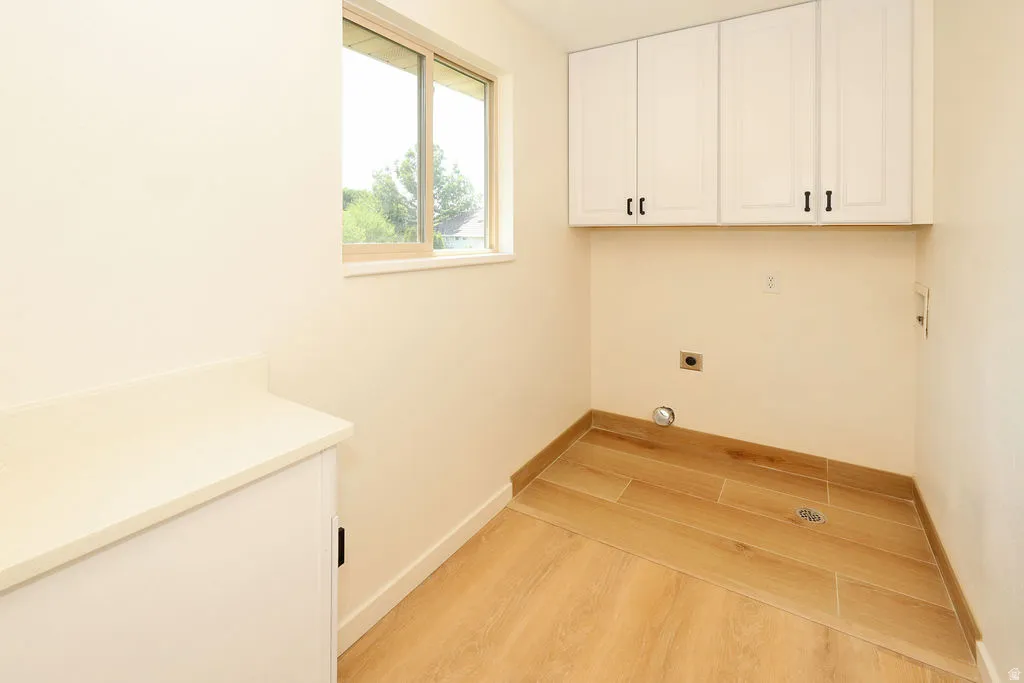 Utility room featuring wood-finish tile flooring, white upper cabinetry with black hardware, and a built-in counter
