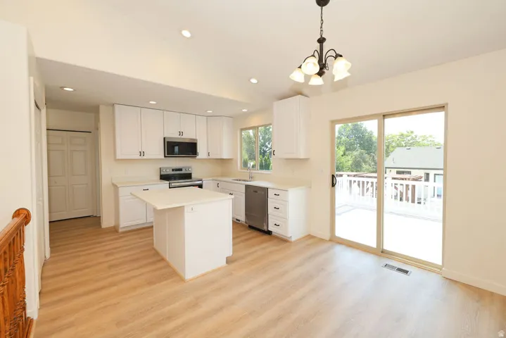 Bright kitchen and dining area featuring white cabinetry, stainless steel appliances, and a central island