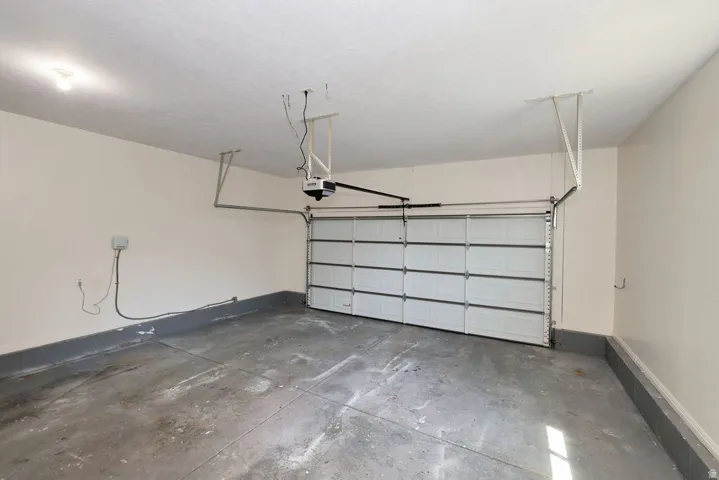 Single-car garage featuring a sectional garage door, concrete flooring, painted walls, and an overhead lighting fixture