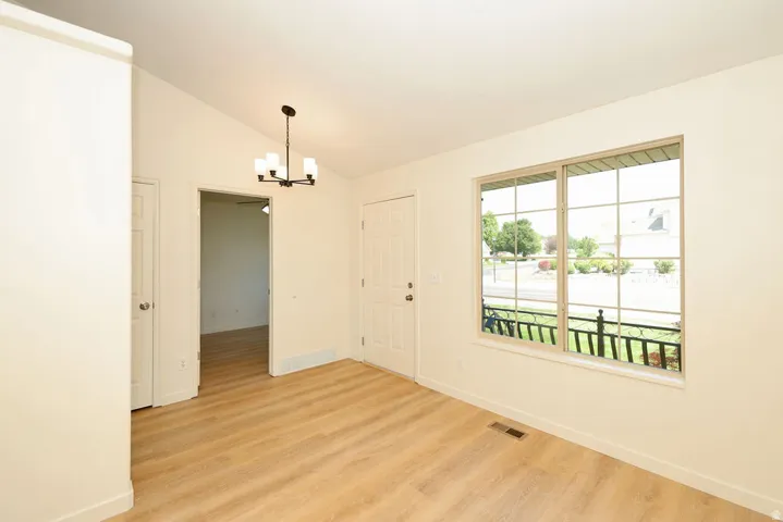 Entry area featuring wood-finish flooring, a contemporary chandelier, and a large window with grilles
