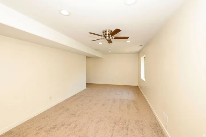 Carpeted room featuring a ceiling fan, recessed lighting, and a single window