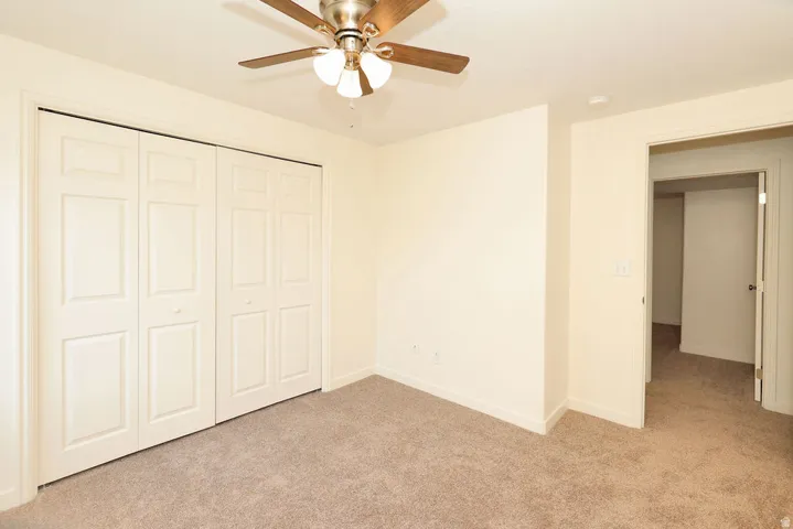 Neutral tone walls with a ceiling fan featuring wood-finish blades and integrated lighting