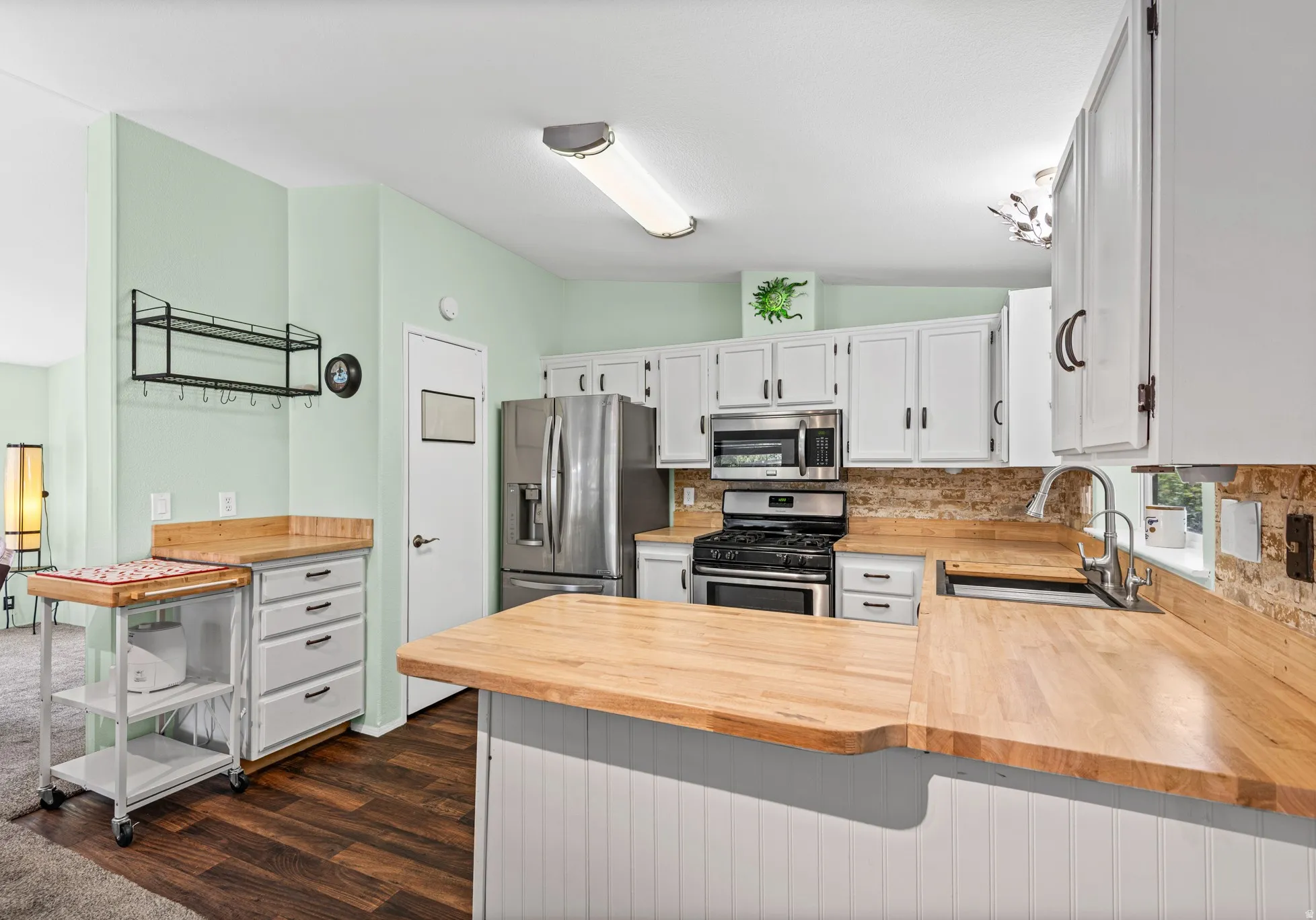 Kitchen featuring wood-finish countertops, white cabinetry, and stainless steel appliances