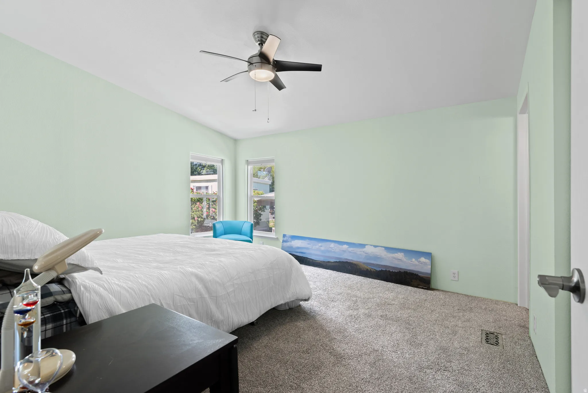 Carpeted bedroom featuring vaulted ceilings, a ceiling fan with integrated lighting, and two windows