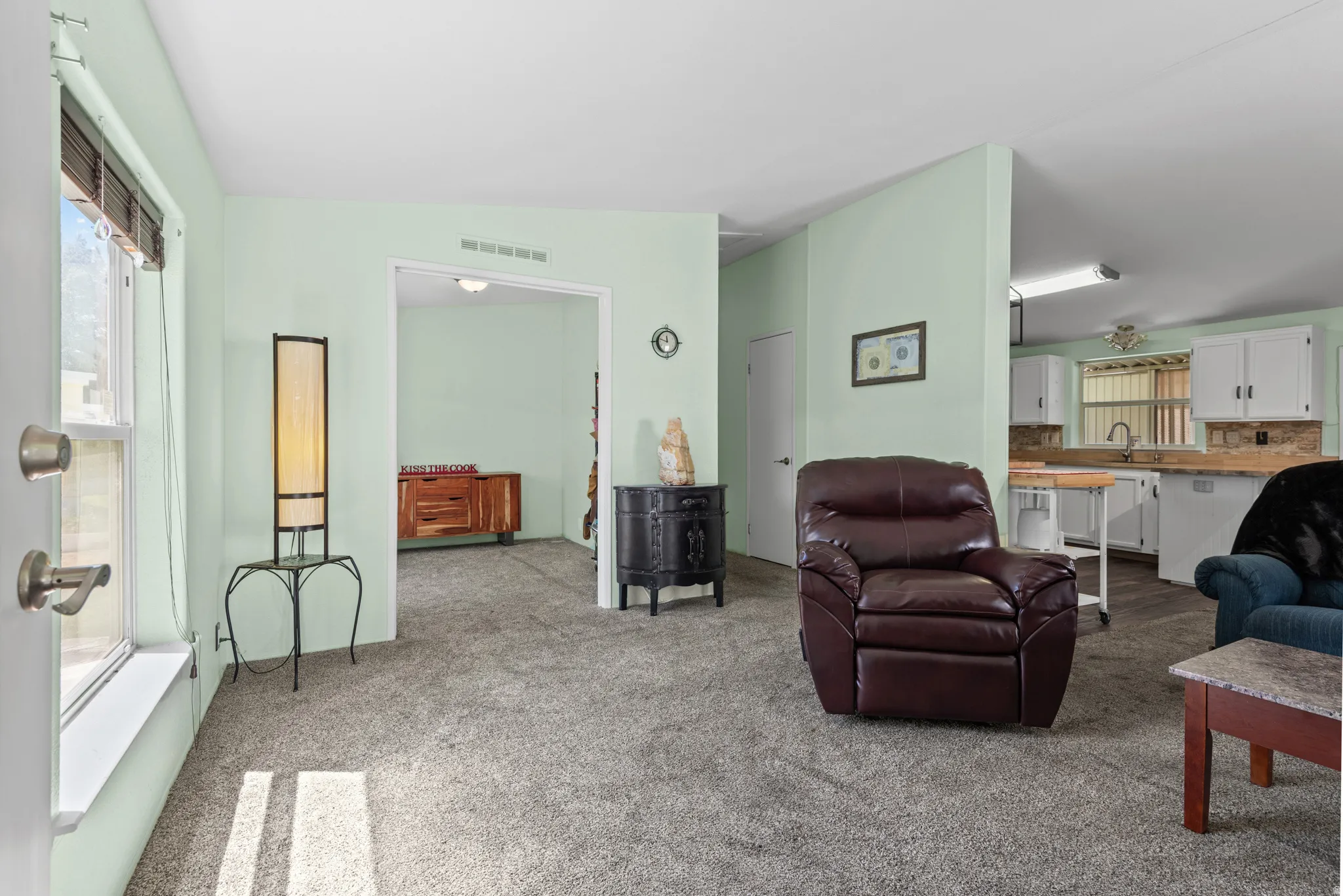 Light green wall paint throughout the living area, featuring grey carpet flooring