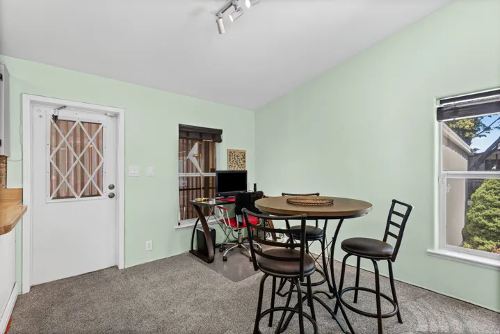 Carpeted interior space with light green walls and a vaulted ceiling