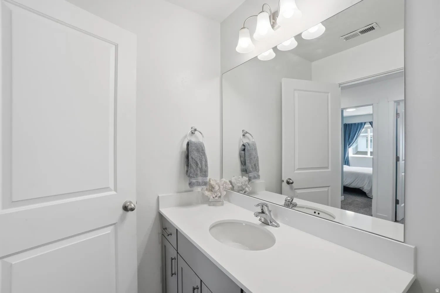 Bathroom vanity featuring a light countertop, integrated sink, and brushed nickel faucet