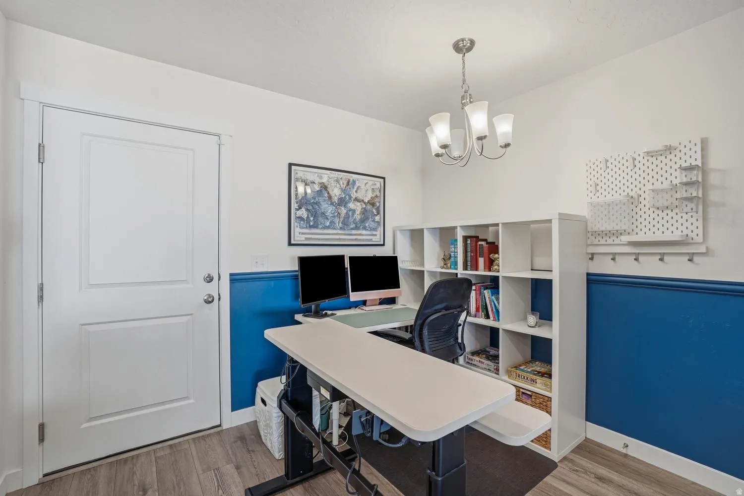 Spacious room featuring wood-finish flooring, a contemporary chandelier, and built-in shelving