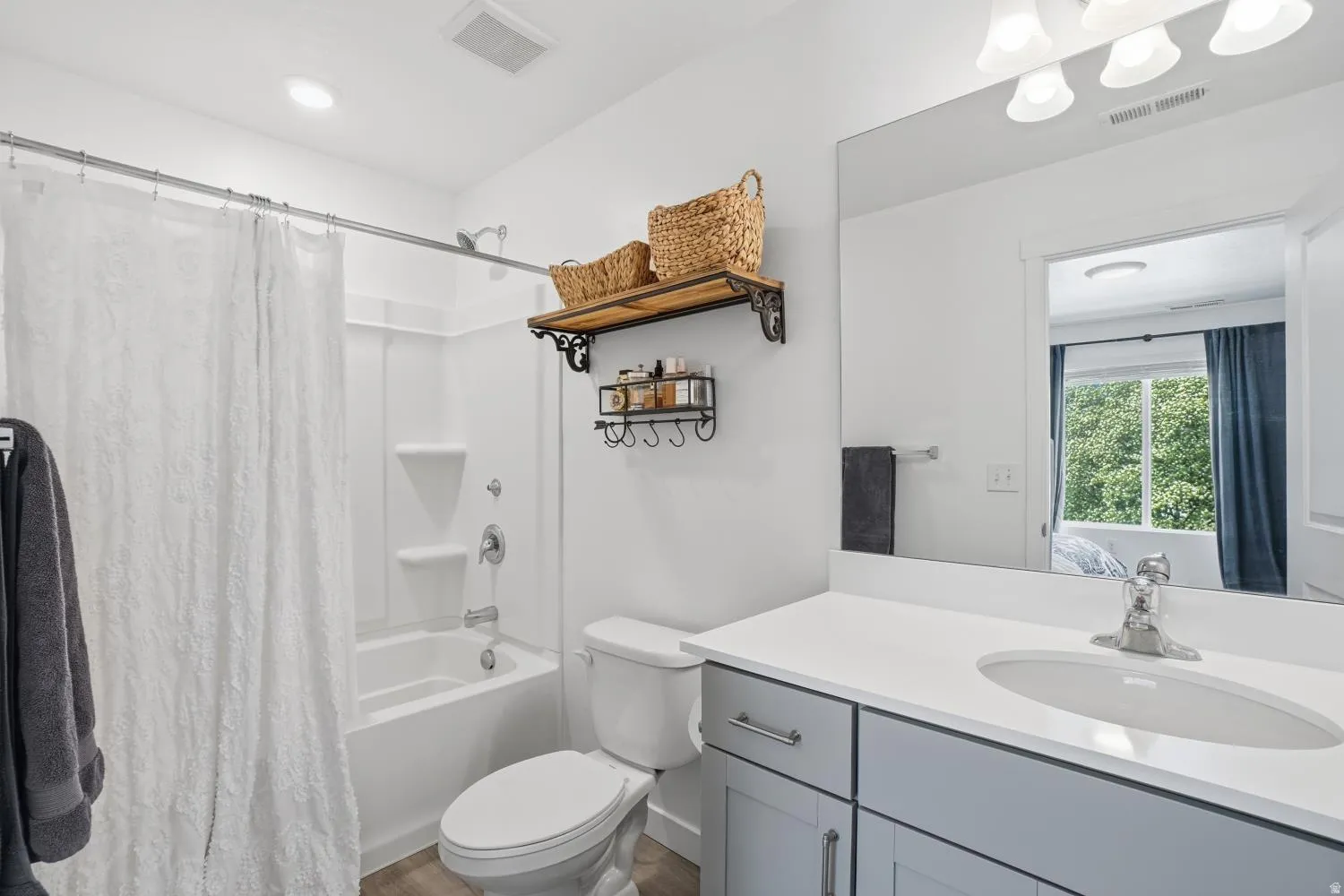 Full bathroom featuring a white single-piece tub and shower unit, a toilet, and a vanity with a white countertop