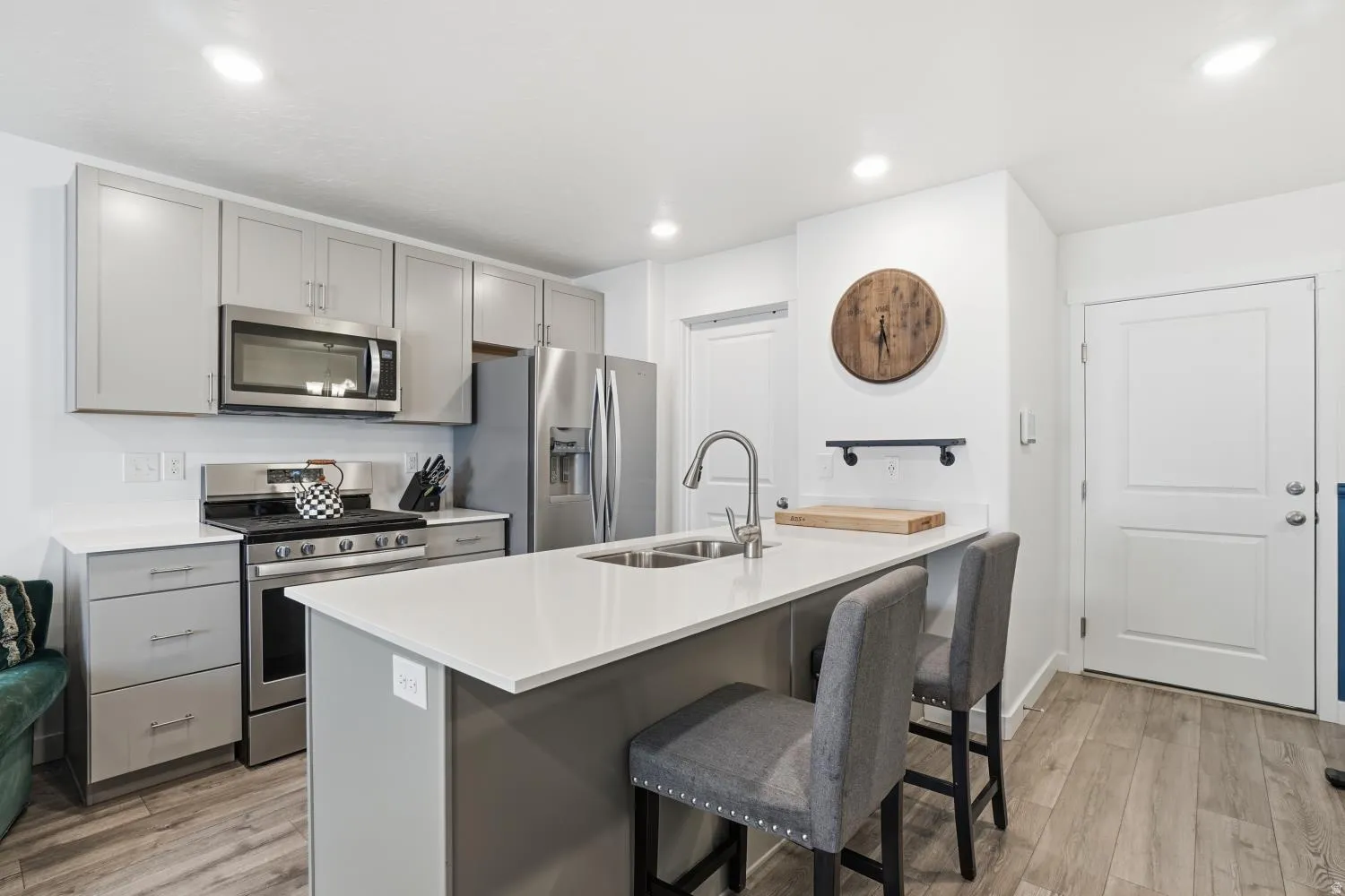 Kitchen featuring light gray cabinetry, stainless steel appliances, and wood-finish flooring