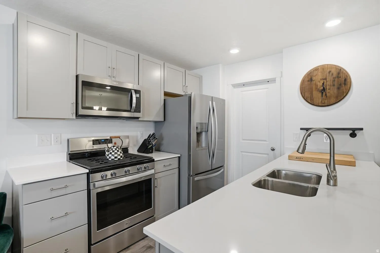 Modern kitchen featuring light gray cabinetry, stainless steel appliances, and a double basin undermount sink