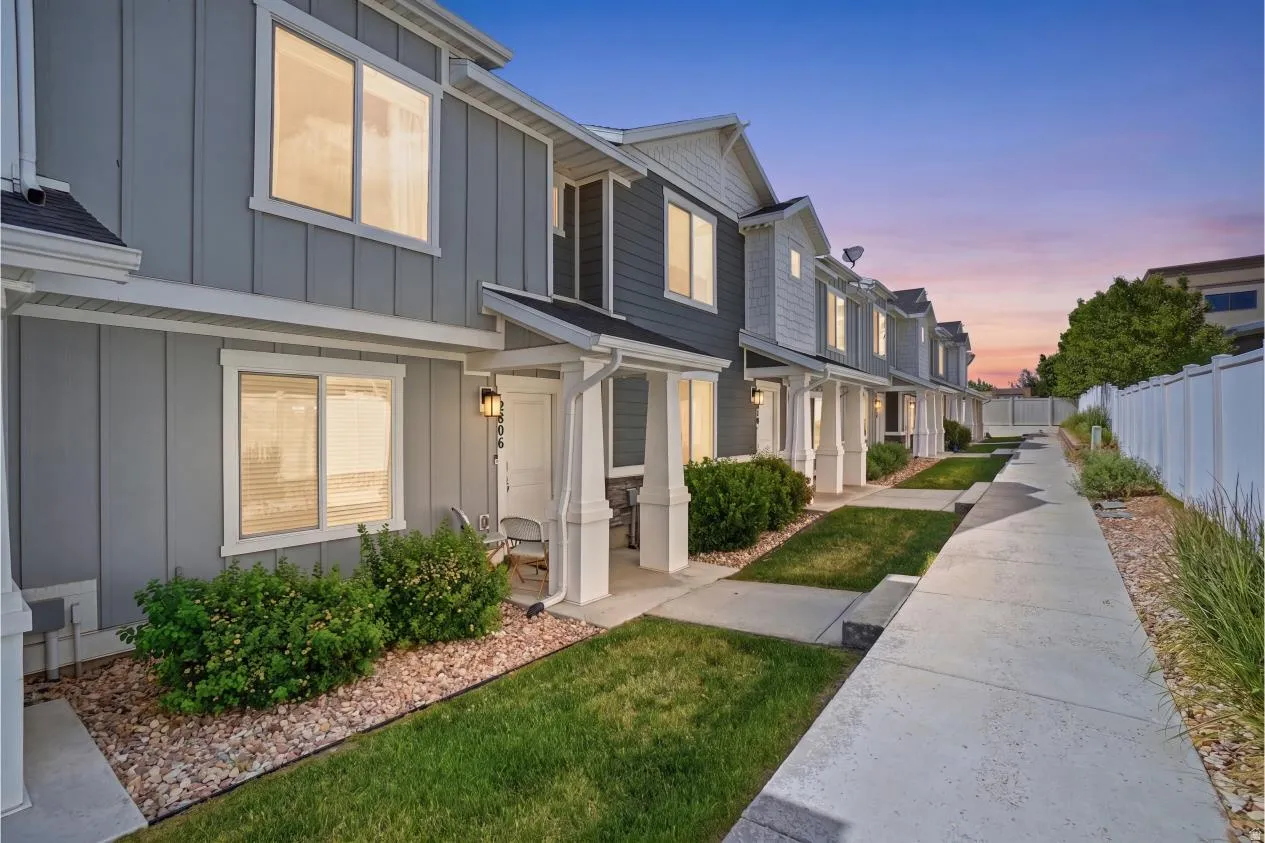 Contemporary townhome exterior featuring light gray siding with white trim accents and dark gray gables