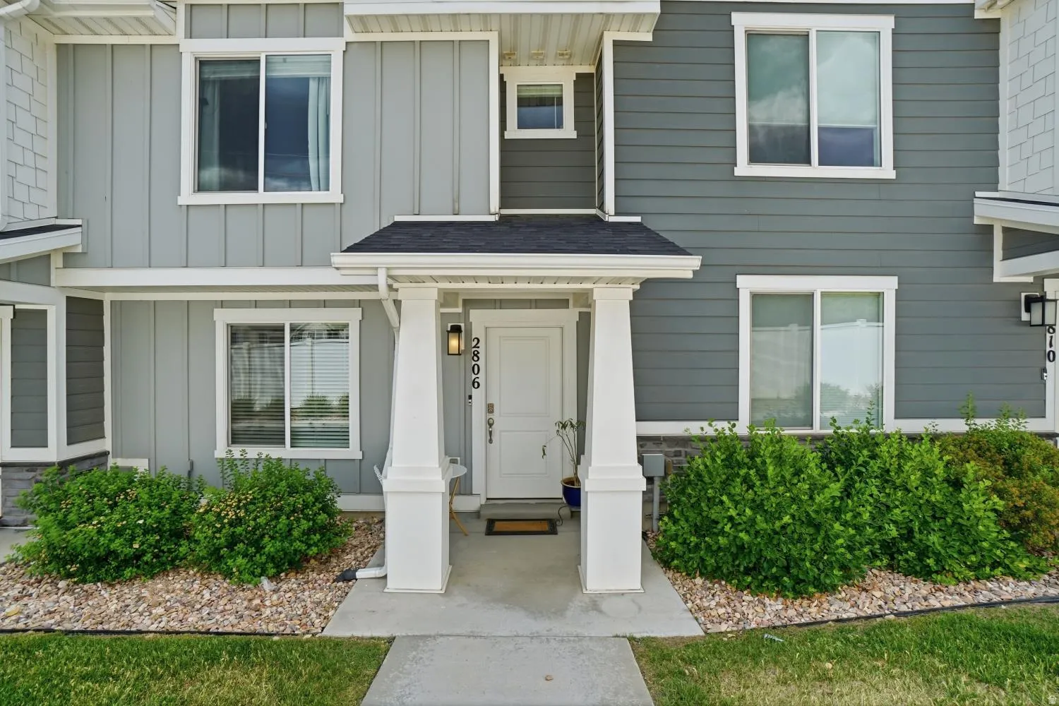 Entryway featuring a white door with transom window, covered porch with white columns, and black exterior lighting