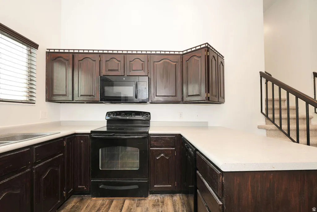 Kitchen featuring dark wood cabinetry, light countertops, and wood-finish flooring