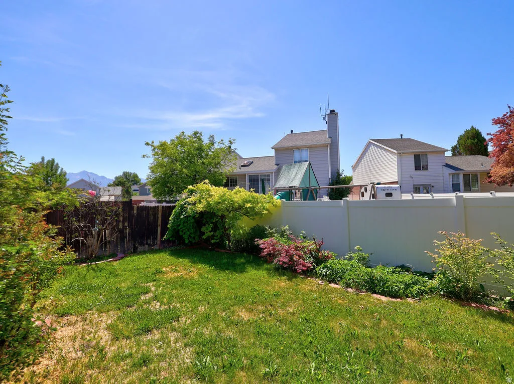 Expansive backyard featuring a green lawn, established landscaping, and a privacy fence