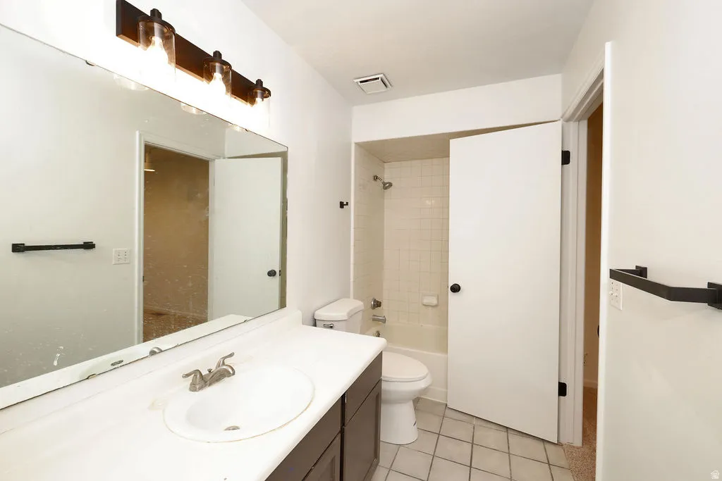 Bathroom featuring a single vanity with dark cabinetry, an integrated sink, and an expansive wall-mounted mirror