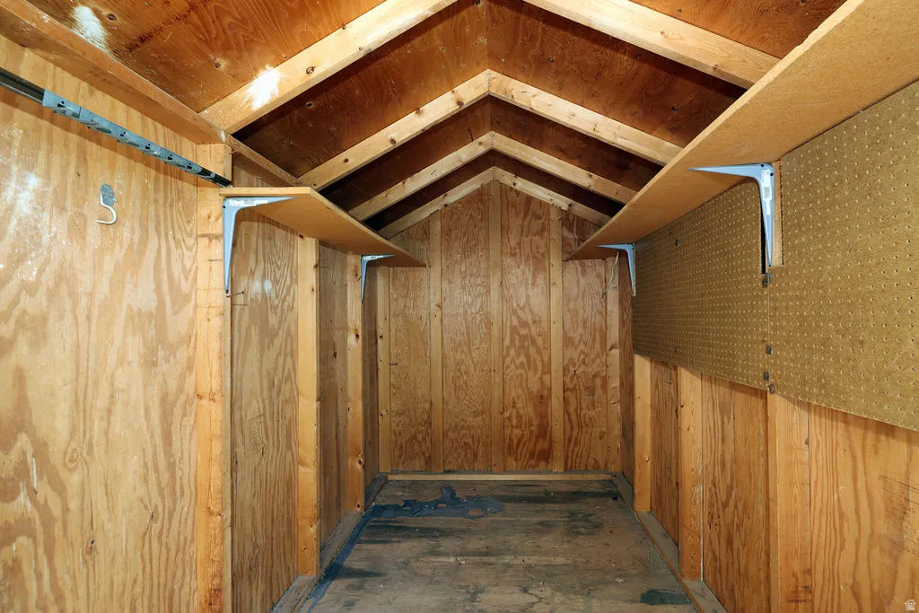 Interior storage space featuring exposed wood framing, wood paneling, and an angled ceiling
