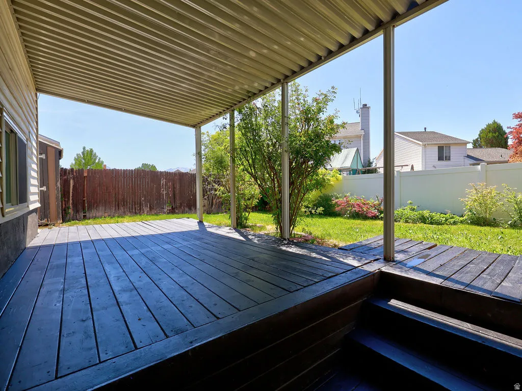 Covered outdoor deck featuring dark-stained wood flooring and multiple steps
