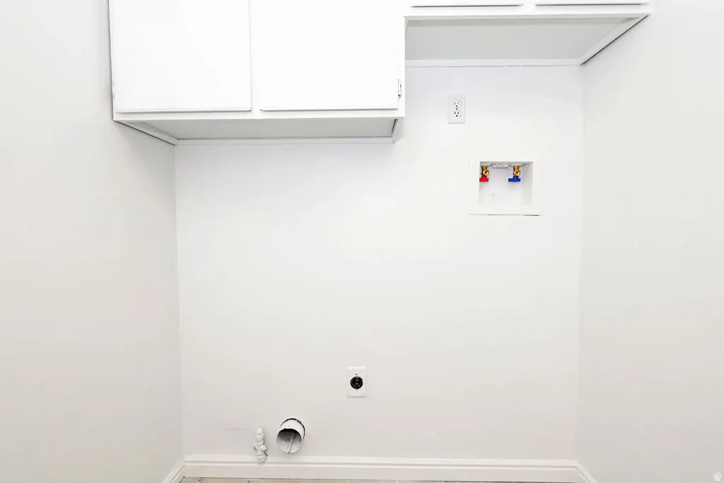Dedicated laundry area featuring white upper cabinetry, electrical outlet, and plumbing hookups