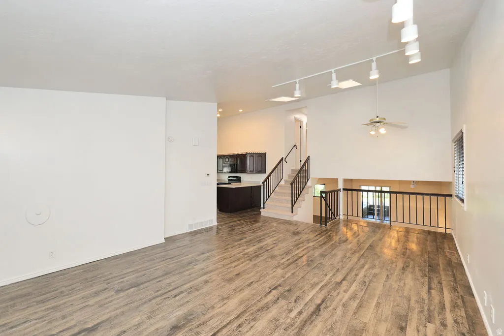 Spacious living area featuring wood-finish flooring, high ceilings, and track lighting
