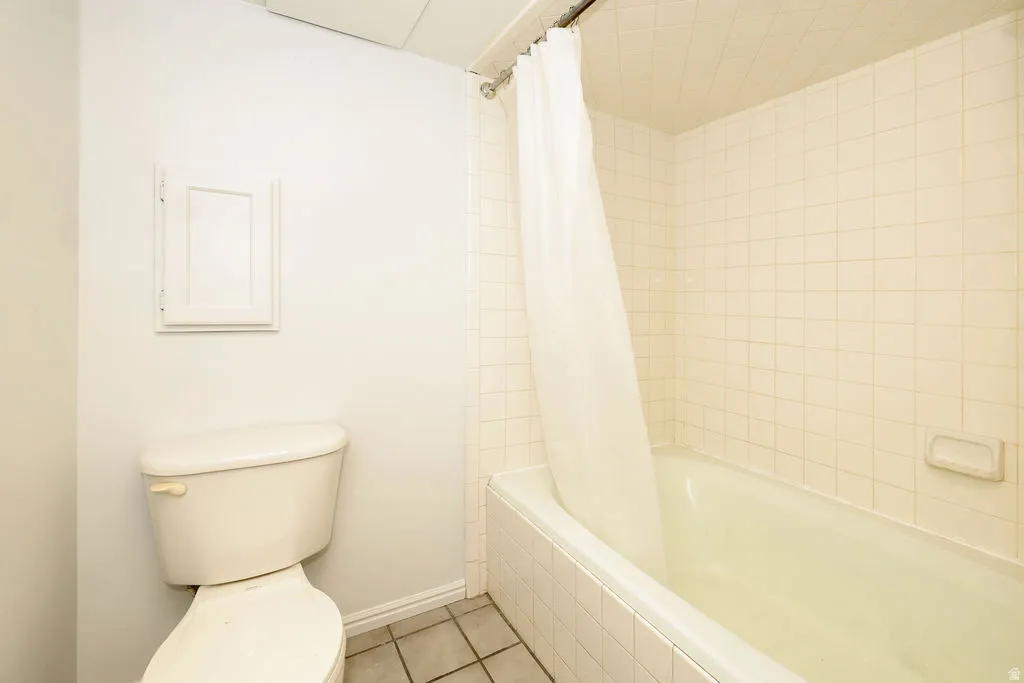 Bathroom featuring a combination bathtub and shower with white subway tile surround, a built-in wall cabinet, and neutral tile flooring
