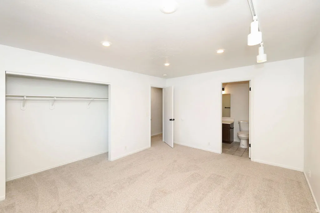 Carpeted room featuring a built-in closet with rod and shelving, recessed lighting, and track lighting