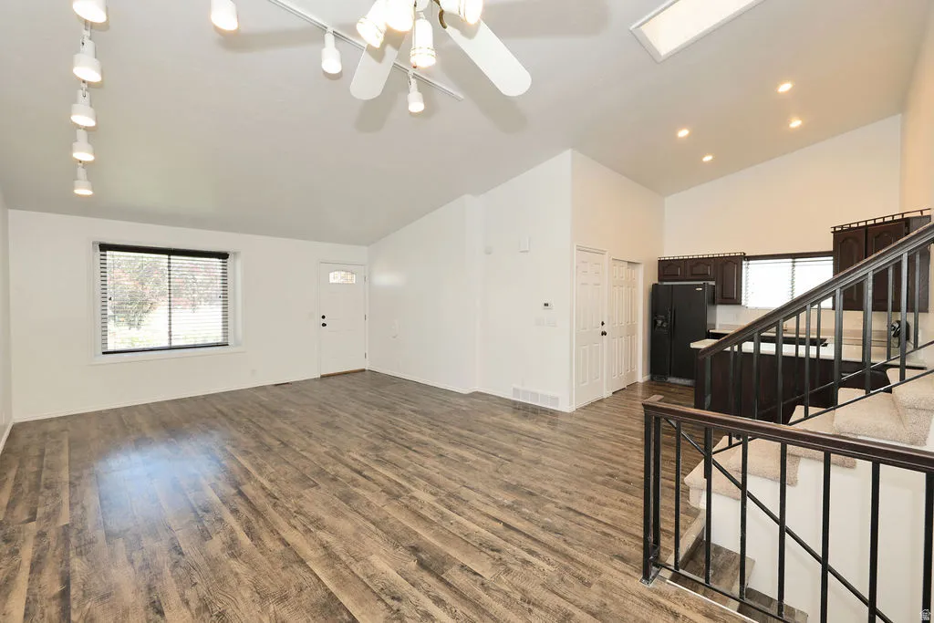 Expansive living area with wood-finish flooring, vaulted ceilings, and track lighting