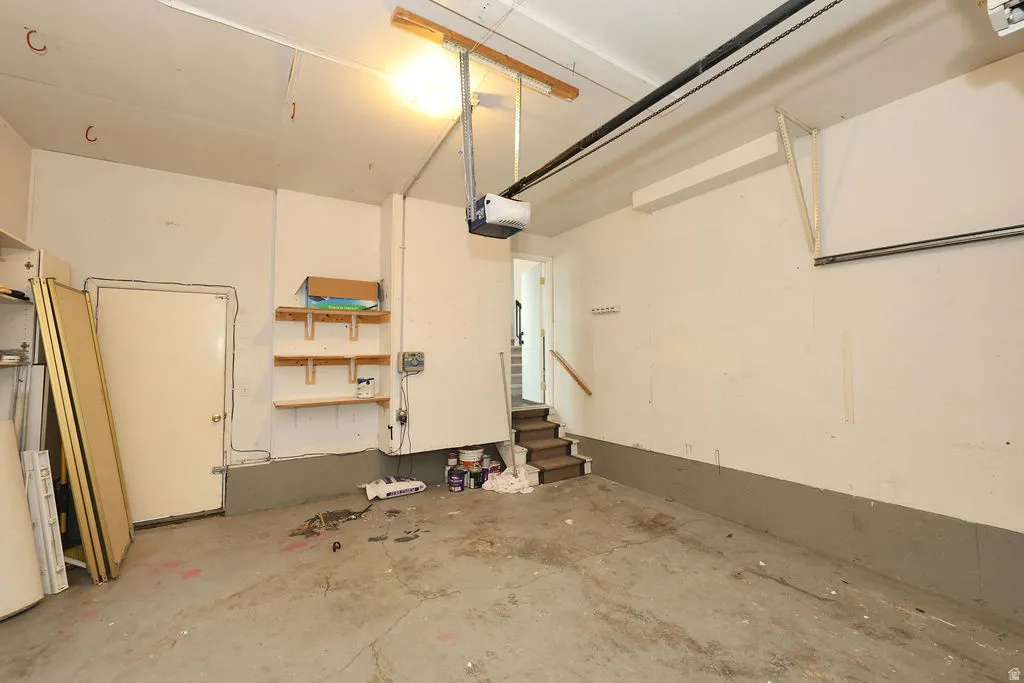 Spacious garage featuring a concrete floor, painted walls, overhead lighting, and built-in shelving